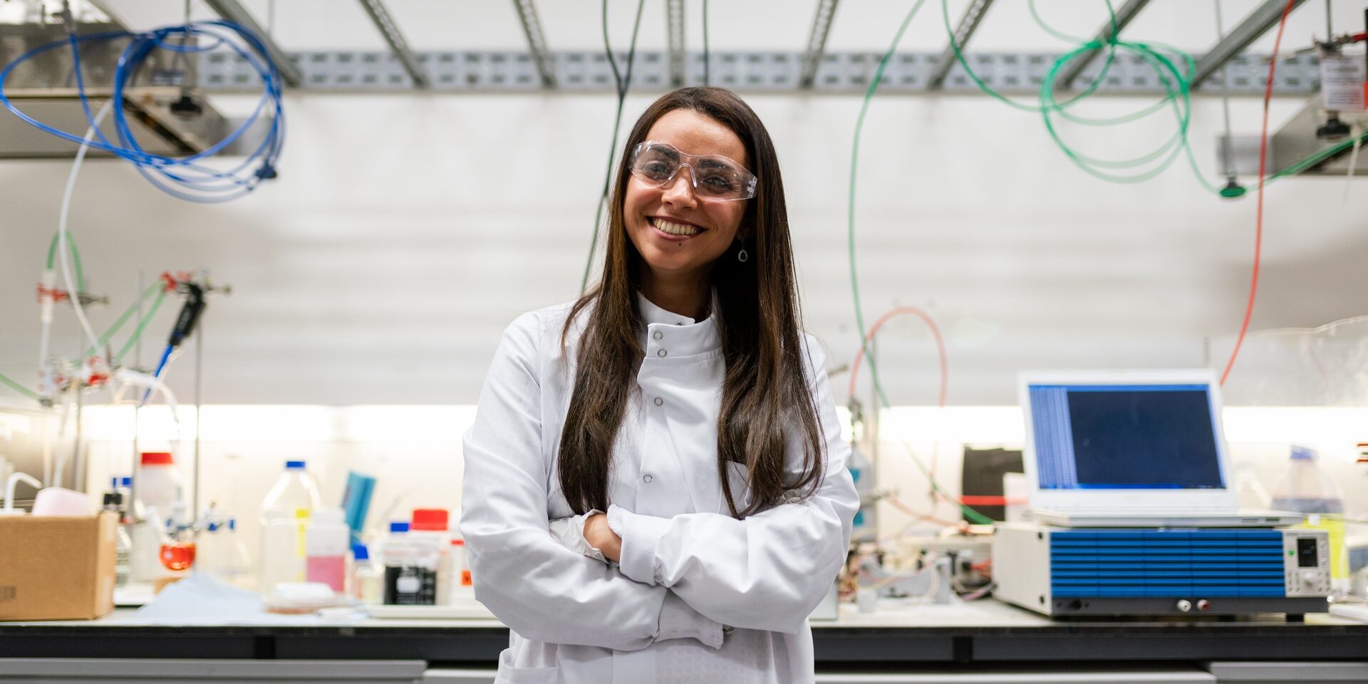 Joven técnica de laboratorio de brazos cruzados y sonriente