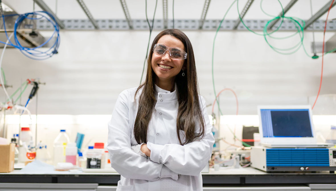 Joven técnica de laboratorio de brazos cruzados y sonriente